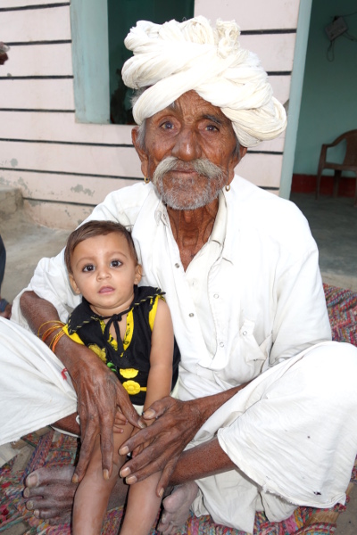 Au sortir du village, à la périphérie, une famille m'invite à entrer dans leur demeure pour me présenter le patriarche. Ce vieil homme avec son arrière petit-fils dans son giron est de la caste des Meghwals. C'est une caste considérait comme très inférieure dans la hiérarchie des castes. Ce sont ces gens qui sont qualifiés d' "Intouchables". Mais je remarque que les membres de cette famille connaissent une évolution positive. La maison est en dur et plutôt confortable. L'un des fils est ingénieur. Des politiques de promotion sociale mises en place depuis l'Indépendance permettent de réelles progressions sociales. Au sortir du village, à la périphérie, une famille m'invite à entrer dans leur demeure pour me présenter le patriarche. Ce vieil homme avec son arrière petit-fils dans son giron est de la caste des Meghwals. C'est une caste considérait comme très inférieure dans la hiérarchie des castes. Ce sont ces gens qui sont qualifiés d' "Intouchables". Mais je remarque que les membres de cette famille connaissent une évolution positive. La maison est en dur et plutôt confortable. L'un des fils est ingénieur. Des politiques de promotion sociale mises en place depuis l'Indépendance permettent de réelles progressions sociales.