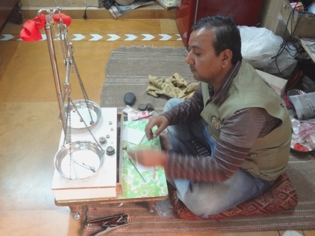 Jeune orfèvre ("Sonar") en train de peser un bijoux en argent pour en déterminer la valeur. Jeune orfèvre ("Sonar") en train de peser un bijoux en argent pour en déterminer la valeur.